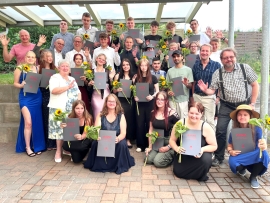 Schüler und Lehrer informieren festlicher Kleidung haben sich unter einem Vordach zum Gruppenbild aufgestellt.