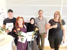 Drei junge Menschen in dunkler Kleidung stehen in der linken Bildhälfte mit Rosen und Dokumenten in der Hand. Rechts stehen zwei Erwachsene.