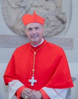 Kardinal Artime im roten Kardinalsgewand vor einer Steinmauer