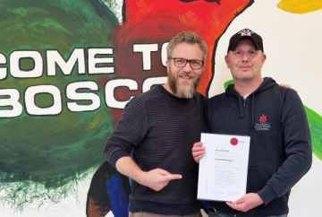 Absolvent Jiri Pacourek (rechts) und Stefan Müller, Einrichtungsleiter von Don Bosco Nürnberg, präsentieren das Abschlusszertifikat der Weiterbildung Straßenpädagogik.