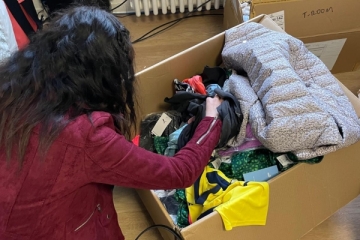 Junge Frau sucht in einer Kiste voll Klamotten, die der Verein Charity Cat für obdachlose Jugendliche im Offenen Treff von Don Bosco Nürnberg gespendet hat