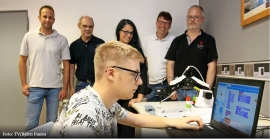 Robin programmiert einen Roboterarm. Hinten von links: Carsten Rausch (Projektleiter Move in Arbeit 4.0.), Michael Müller (Leiter BBS Gewerbe und Technik), Katja Ferring (Klassenlehrerin BBS GuT), Wolfgang Marx (Ausbildungsleiter Helenenberg), Markus Zehren (Helenenberg).