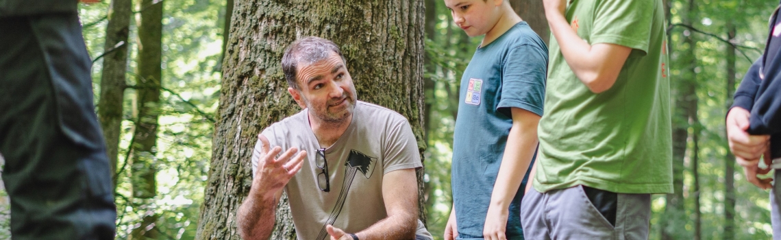 Ein Mann kniet im Wald im Gespräch.