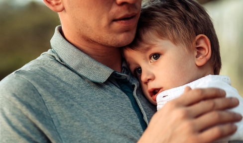 Vater hält Kind, das Tränen in den Augen hat, liebevoll im Arm