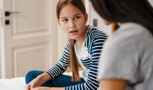 Eine Jugendliche spricht mit ihrer Mutter, von der nur der Rücken zu sehen ist.