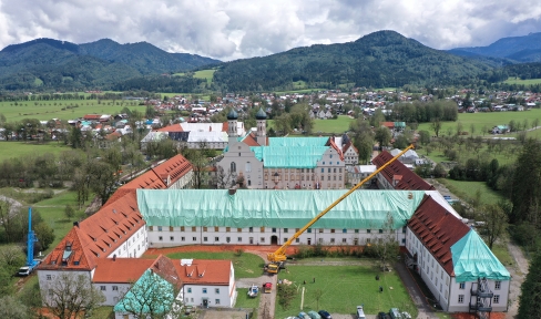 Das Kloster Benediktbeuern nach dem Unwetter aus der Vogelperspektive; die Dächer sind mit türkisblauen und weißen Planen überdeckt.