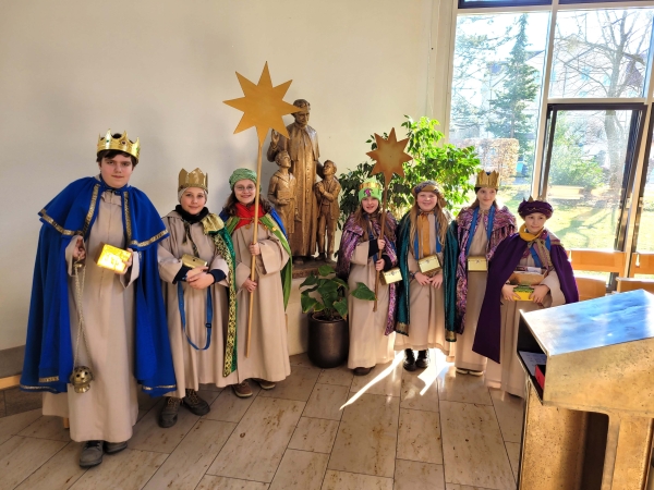 Die Sternsinger stehen in der Hauskapelle vor der Don Bosco Statue.